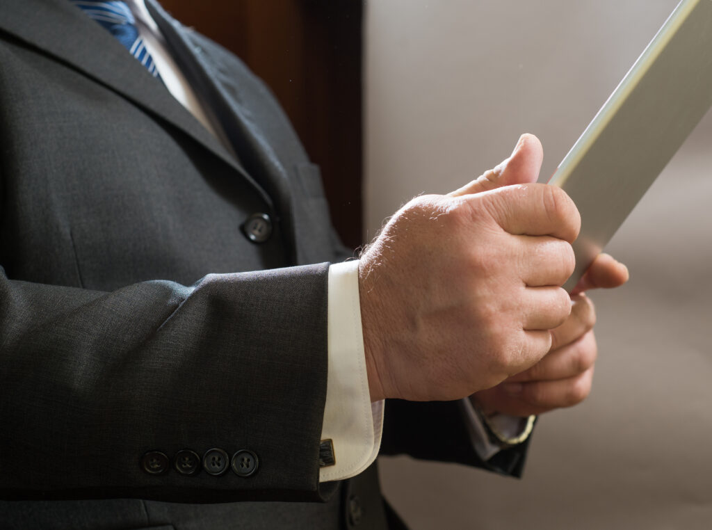 Close - up of adult businessman standing in suit and use tablet