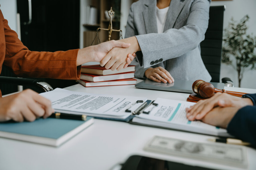 Lawyer shaking hands with client after discussing final contract agreement.