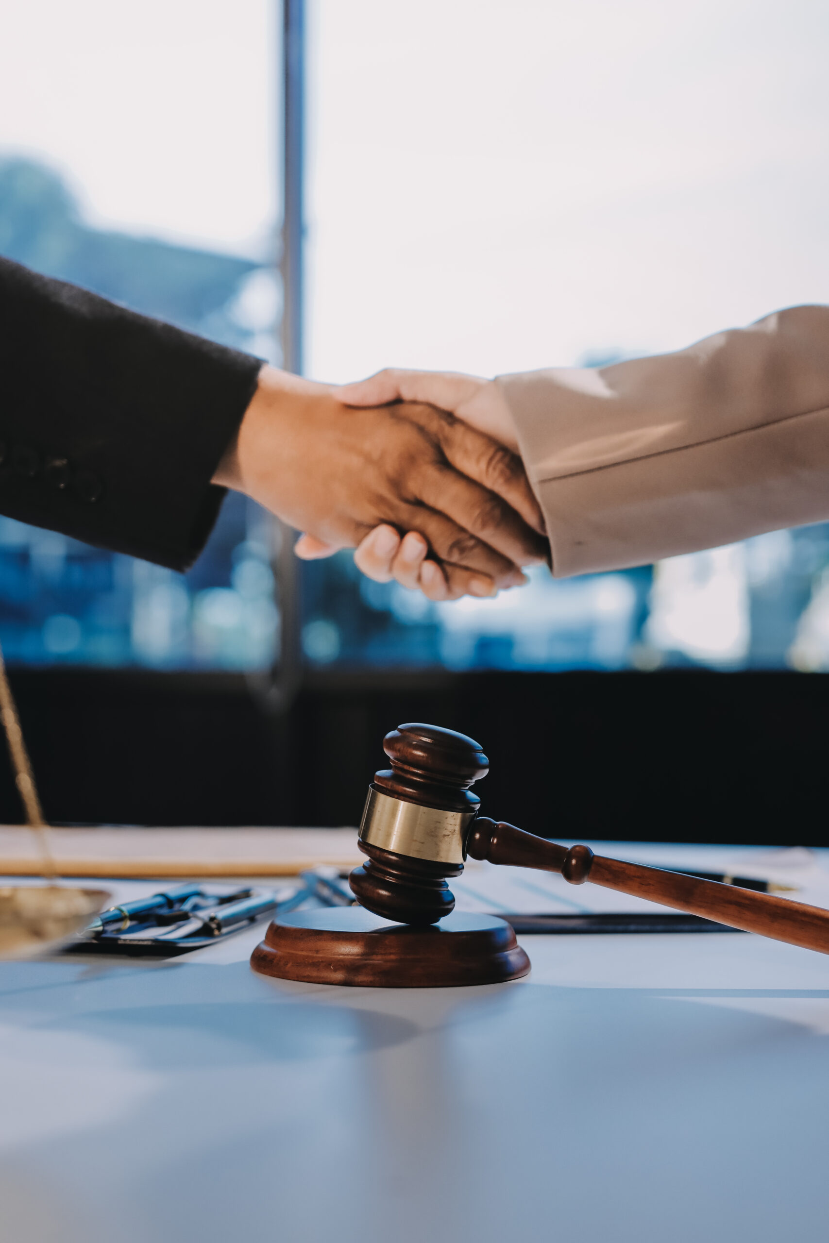 Two businesspeople are shaking hands in a law office with a scal